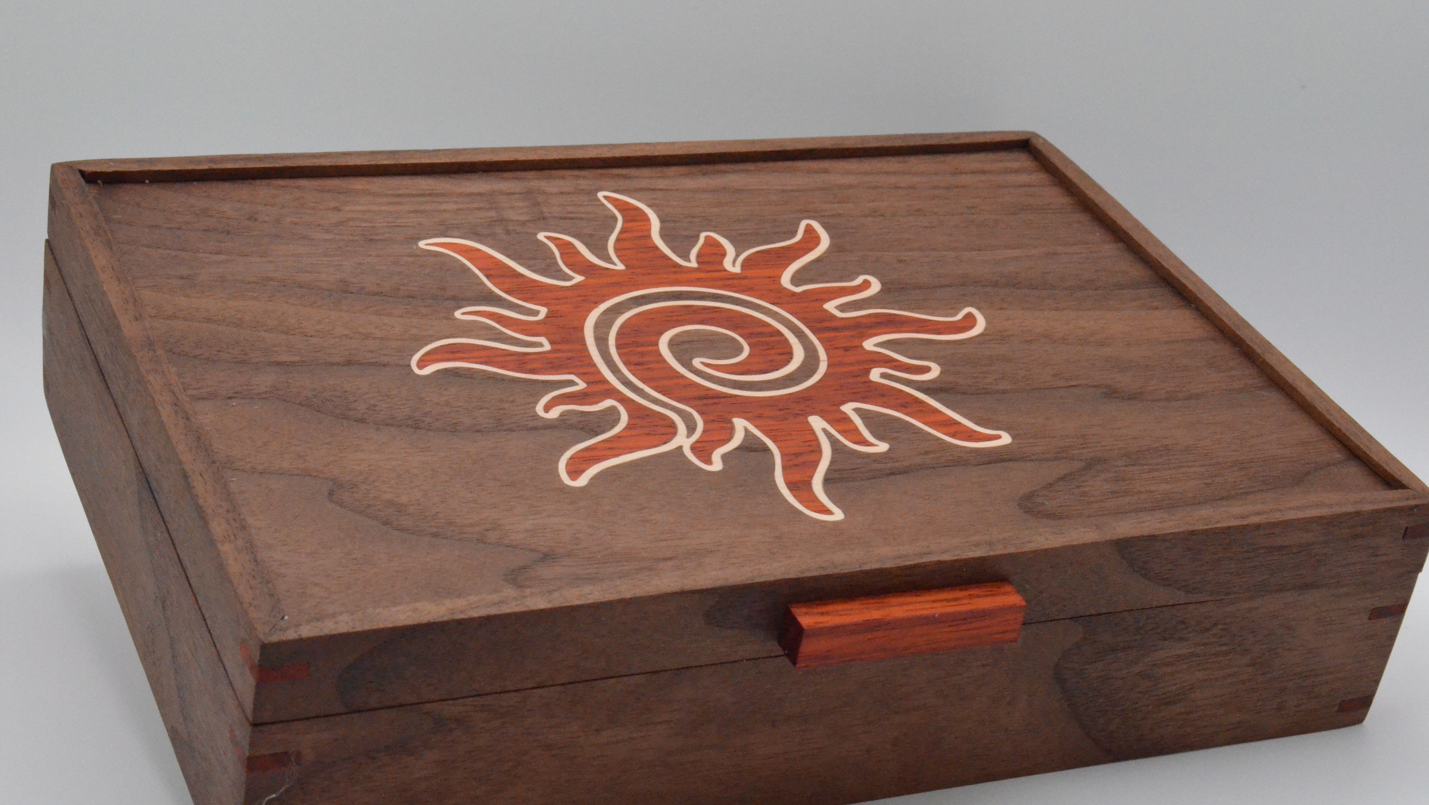 A walnut box with an inlaid sun motif, using natural wood contrast for color.