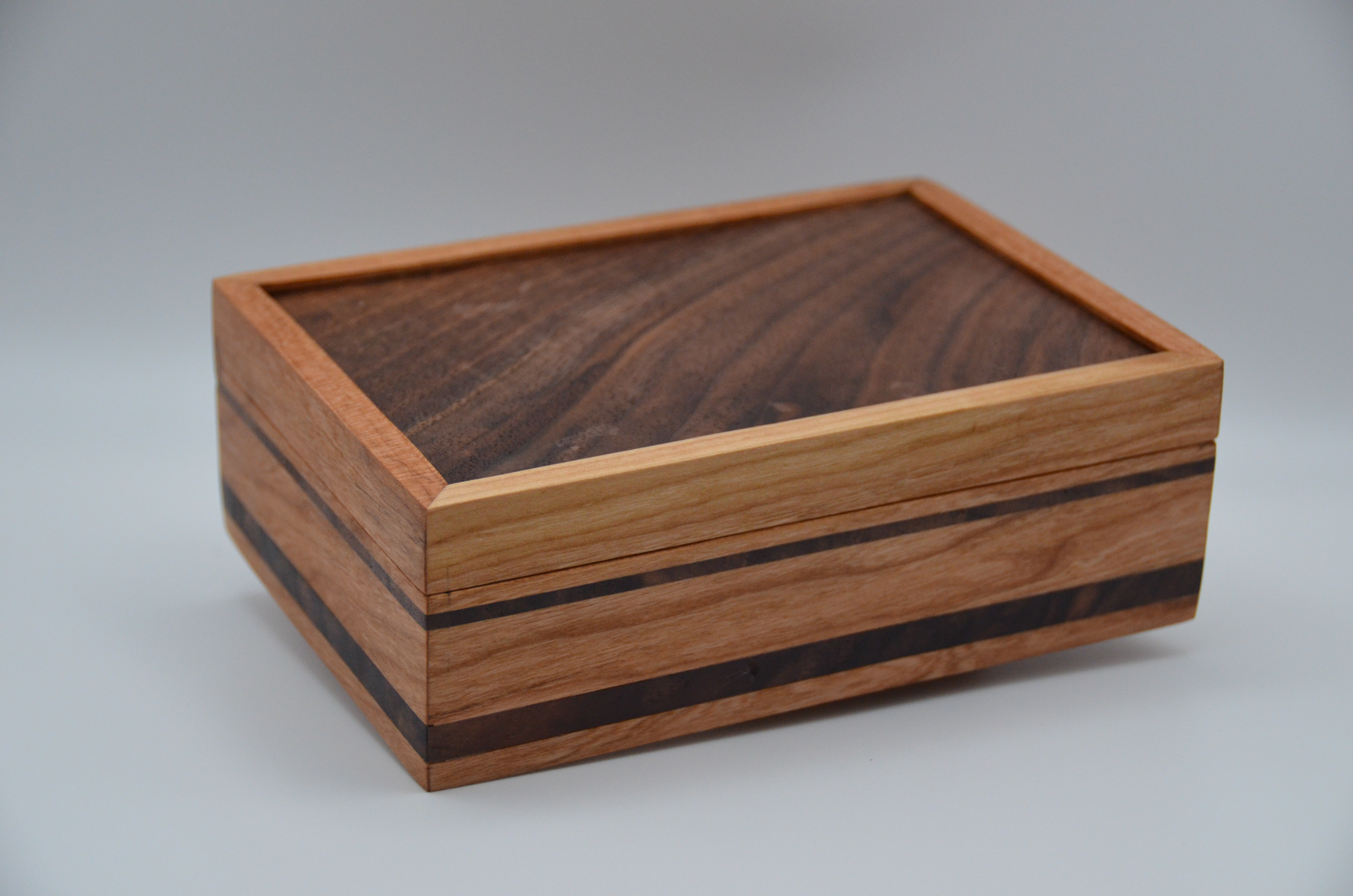 Wooden box at an angle, showing depth, edges, and how the lid relates to the base.