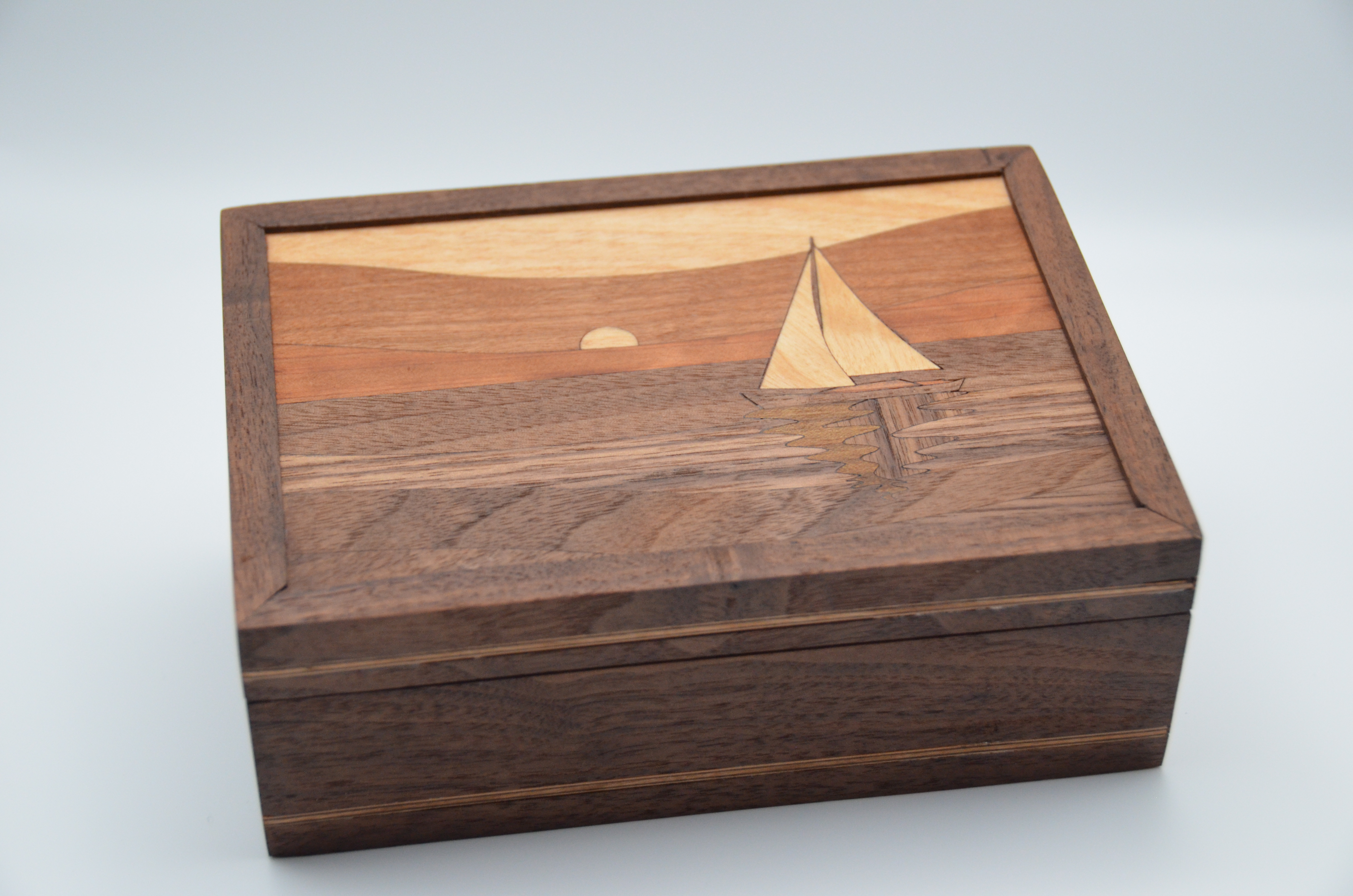 Small wooden box in profile on a neutral surface, showing overall form and shadow.